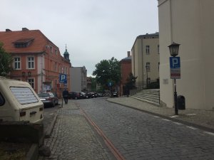 widok ulicy Franciszkańskiej w Gnieźnie i zaparkowanych z boku ulicy samochodów