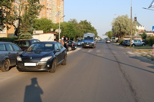 widok drogi o poranku z lewej strony auta, w oddali postaci osób i policjanta
