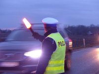policjant z żółtej kamizelce zatrzymuje auto do kontroli drogowej