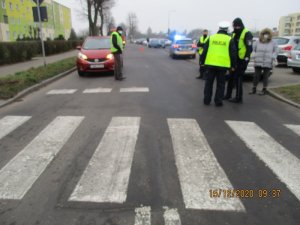 pasy na jezdni i policjanci podczas czynności po wypadku