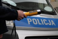 policjant trzyma alkomat na tle radiowozu