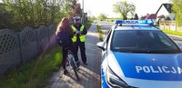 policjant i kobieta kierująca rowerem, z prawej strony radiowóz