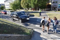 Trzy dziewczynki machają na przejściu do kierowcy, który zatrzymał się, by je przepuścić.