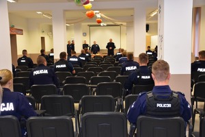 zdjęcie kolorowe, wykonane z końca auli, kilku policjantów siedzących tyłem na krzesłach