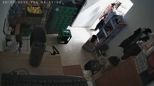 Zdjęcie kolorowe, widok na sklep z góry z kamery sklepowej. Widać mężczyznę około 30 lat wchodzącego do pomieszczenia.