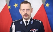 Mężczyzna w mundurze na tle flag Uni Europejskiej i Polski