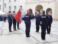 Młodzi policjanci na placu  składają ślubowanie. W tle poczet sztandarowy policji w Poznaniu.