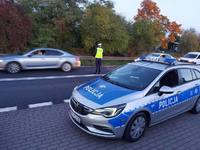 Zdjęcie drogi. Policjant bada trzeźwość kierującego pojazdem.