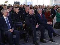 policjanci i cywile siedzą na krzesłach, kilkadziesiąt osób