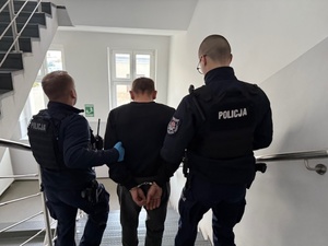 Policjanci schodzą z zatrzymanym po schodach.