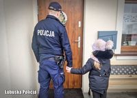 Na zdjęciu policjant trzyma dziecko za rękę.