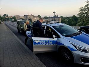 Policjant i policjantka przy radiowozie.