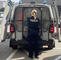 Policjantka zamyka tylne drzwi radiowozu.