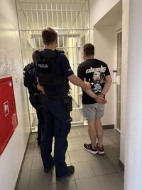 Policjanci wykonują czynności z zatrzymanym mężczyzną.