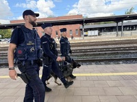 Przewodnik z psem policyjnym, funkcjonariusz Straży Ochrony Kolei i policjantka prewencji podczas patrolu dworca PKP.