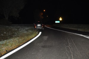 Z daleka na drodze widoczny ciemny samochód.