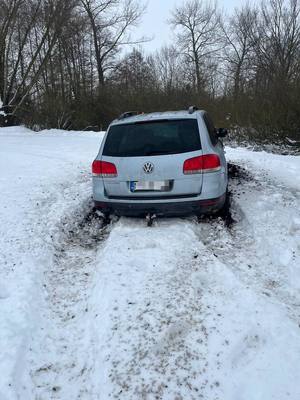 Srebrne auto osobowe, zaparkowane na polu w śniegu, widoczne od strony tyłu.