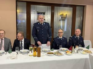 policjanci i osoby cywilne przy stole nakrytym na spotkanie opłatkowe