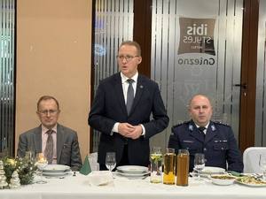 Trzech mężczyzn przy świątecznym stole. Jeden z nich przemawia.