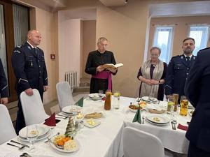 Ksiądz przemawia przy świątecznym stole.