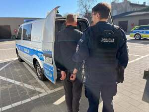 Podejrzany podczas doprowadzania przed policjantów do radiowozu.